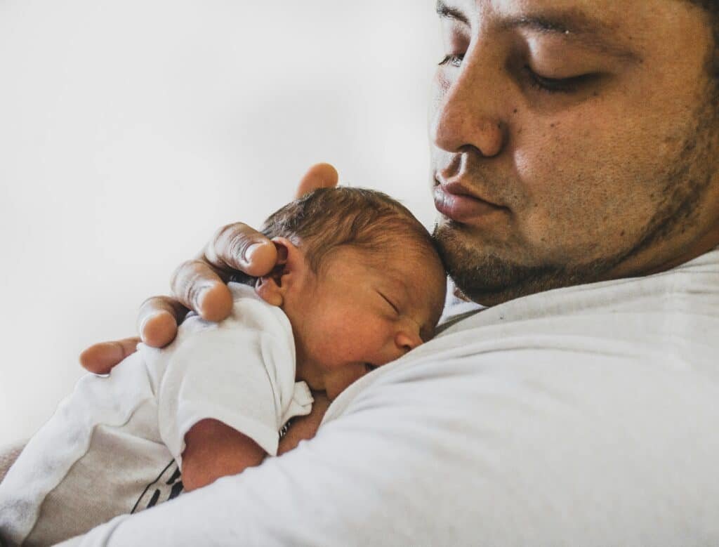 A heartwarming scene of a father gently holding his sleeping newborn baby, showcasing love and family connection. baby sleep calculator